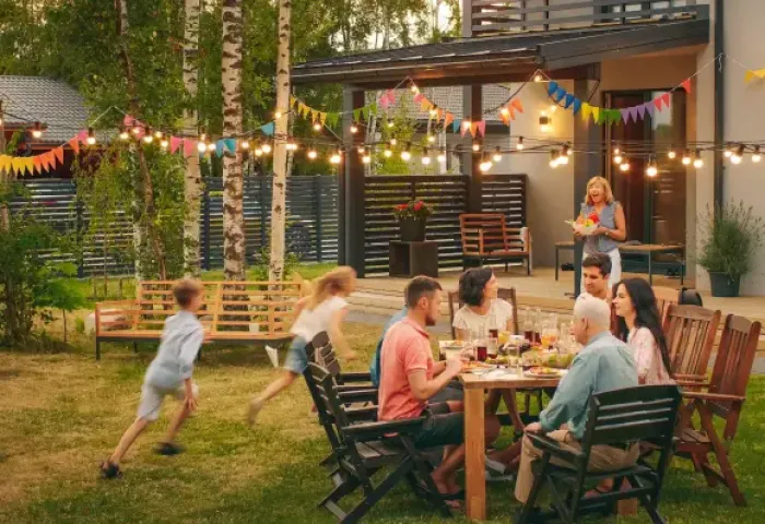 Familie im Vorgarten beim Essen und spielende Kinder